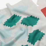 Babydecke in naturweiss grün blau und weich in mehrfarbigem grafischem Muster aus Merinowolle und Mohair für zeitloses Baby Interieur in frischem Design mit Nachhaltigkeit als das perfekte Geschenk für Neugeborene im Babybett