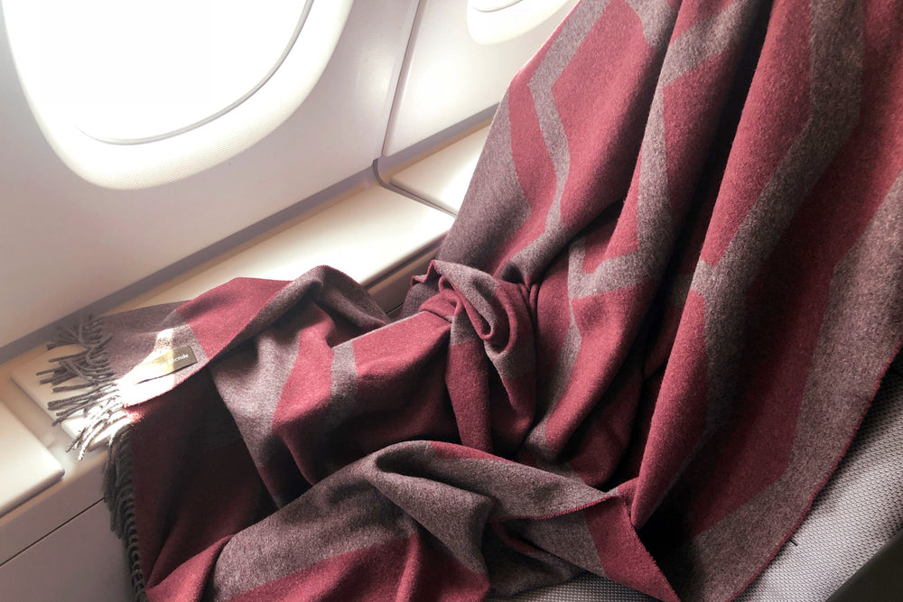 Weiche hochwertige Reisedecke in Aubergine und Grau aus Yak und Merino Wolle als Begleiter im Flugzeug zum Einkuscheln und Zudecken bei Langstreckenflug und Nachtflug