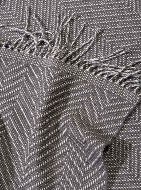 Tagesdecke und Bettüberwurf in grau Fischgrät Muster aus Merino gewebt für Schlafzimmer Interieur für Stil mit luxuriösem Design und Nachhaltigkeit und Handwerkskunst für Dekor und Cozy Gefühl auch als Fussdecke und in Gaskrise bei Energie Sparen und Heizen im kalten Winter
